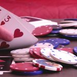 Hand holding cards on table with poker chips